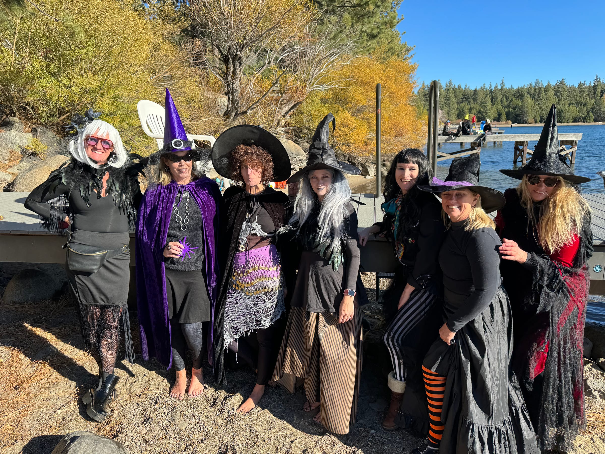 A group of costumed witches pose together on the shore of Donner Lake.