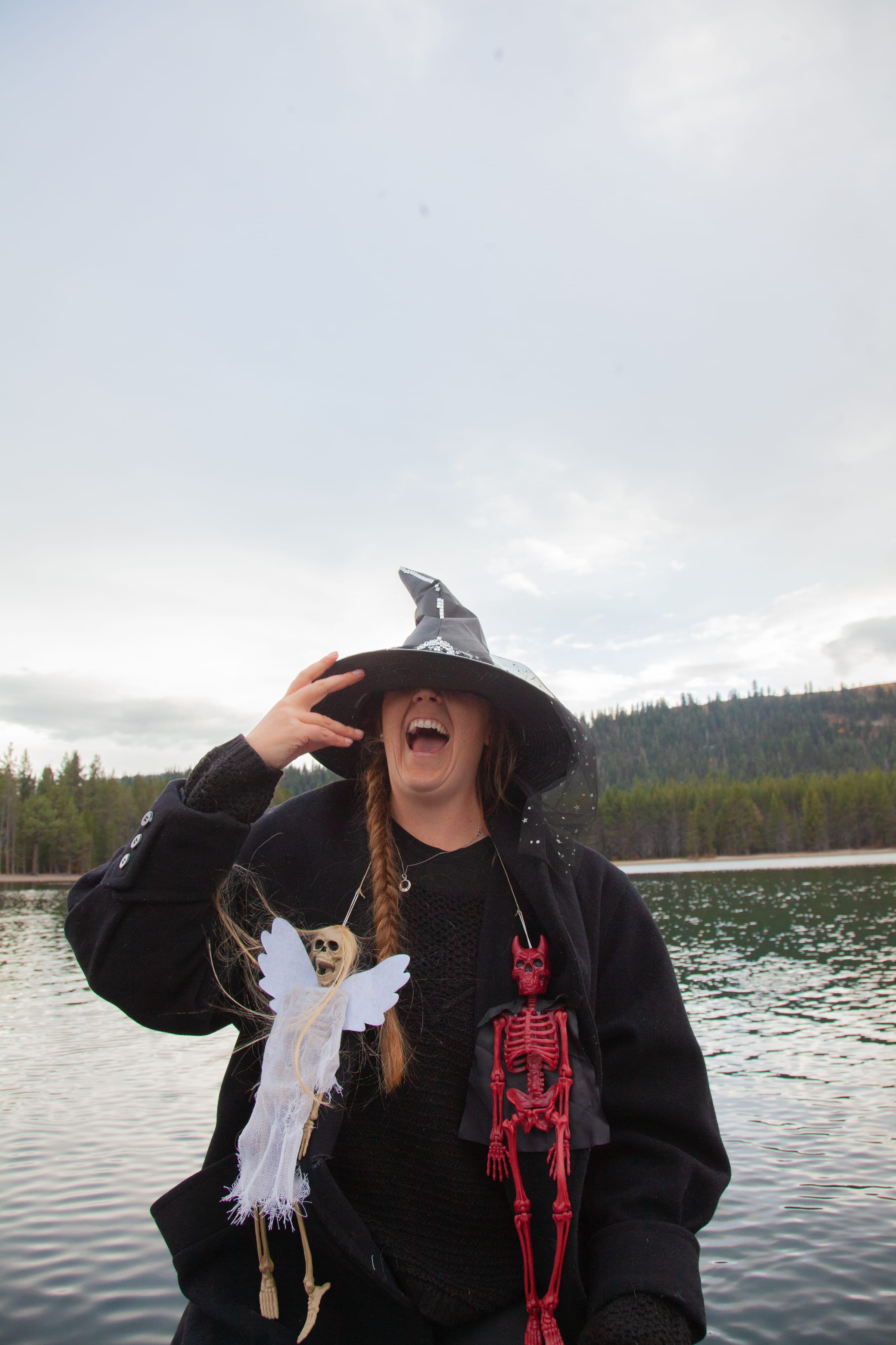 A laughing witch in a pointed hat holds skeleton decorations at Donner Lake.